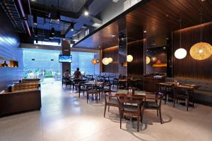 a restaurant with tables and chairs and people in the background at Midtown Hotel Surabaya in Surabaya +46 photos