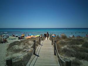 a wooden pathway to the beach with people on it at HG Jardín de Menorca in Son Bou