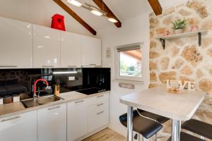 a kitchen with white cabinets and a stone wall at Holiday home Villa Juli in Šibenik