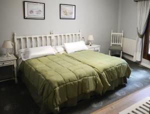 a bedroom with a large bed with a green blanket at Hotel Tres Carabelas in Baiona