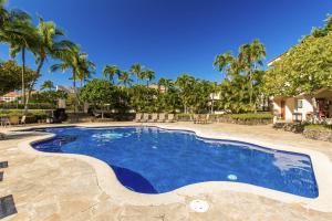 a swimming pool with blue water and palm trees at 2 Bed 2 Bath Apartment in Shores at Waikoloa in Waikoloa