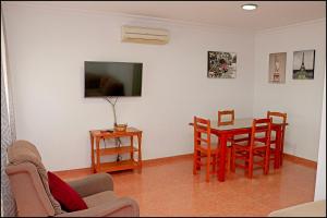 - un salon avec une table, des chaises et une télévision dans l'établissement Dalí al Mar, à Conil de la Frontera