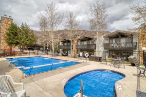 a pool at a resort with tables and chairs at 1 Bath Studio Apartment in Snowmass Village in Snowmass Village