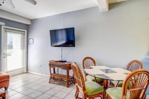 a dining room with a table and a tv on the wall at Sand & Surf Sea Mist Condos in Port Aransas