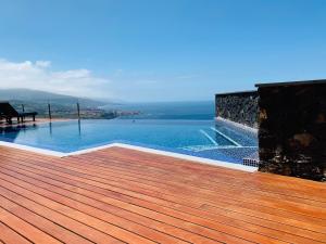 einen Pool mit einer Holzterrasse am Wasser in der Unterkunft Villa OCEAN Infinity heated pool optional in Santa Úrsula