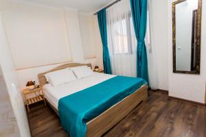 a bedroom with a bed with blue curtains and a mirror at Sorriso Mamaia Nord in Mamaia Nord