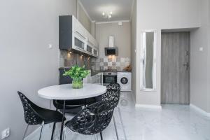 a kitchen with a white table and black chairs at Elite Apartments Piwna Premium in Gdańsk