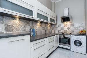 a kitchen with white cabinets and a washer and dryer at Elite Apartments Piwna Premium in Gdańsk +20 photos