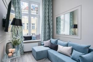 a living room with a blue couch and a window at Elite Apartments Piwna Premium in Gdańsk