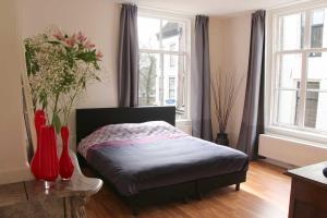 a bedroom with a bed and two windows at B&B Utrecht Domkwartier in Utrecht