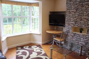 a living room with a tv and a stone wall at Chasewood Court in Hendon