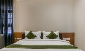 ein Schlafzimmer mit einem großen Bett mit grünen und weißen Kissen in der Unterkunft Treebo Trend Casino in Kozhikode