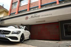 a white car parked in front of a garage at Emakhosini Self-Catering Apartments in Durban