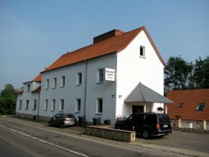 un edificio blanco con coches estacionados frente a él en Gästehaus Perrin en Bliesmengen-Bolchen
