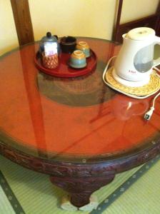 a glass table with a tea pot and a hat on it at Rakucho Ryokan in Kyoto