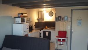 una pequeña cocina con electrodomésticos blancos y una silla roja en L'Océane ( Résidence La Joséphine ), en Les Sables-dʼOlonne