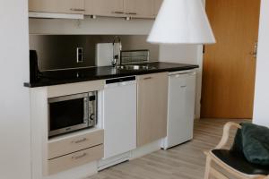 a kitchen with a sink and a microwave at Hotel Sandvig Havn in Allinge