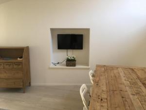 a dining room with a table and a television on a wall at Appartamenti Ora del Garda in Nago-Torbole