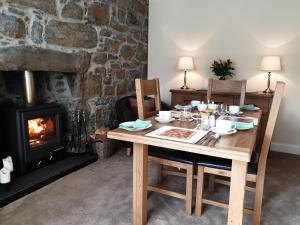 une table en bois avec des chaises et une cheminée dans l'établissement Kirk Cottage, à Tobermory