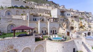 a large stone building with a swimming pool on a hill at Kayakapi Premium Caves Cappadocia in Urgup