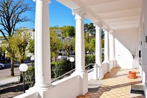 un porche blanco con columnas y una acera en Wilhelms Hostel im Ostseebad Sellin, en Ostseebad Sellin