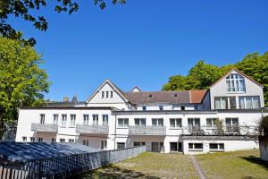 un gran edificio blanco con una valla delante en Wilhelms Hostel im Ostseebad Sellin, en Ostseebad Sellin