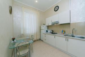 a kitchen with white cabinets and a table with chairs at Apartment on Saksahanskoho Street in Kyiv