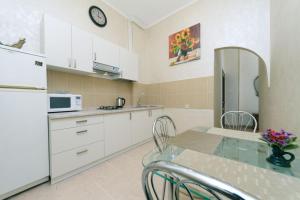 a kitchen with white cabinets and a table with chairs at Apartment on Saksahanskoho Street in Kyiv