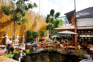 a restaurant with a pond and tables and chairs at Villa Cha-Cha Banglumphu in Bangkok