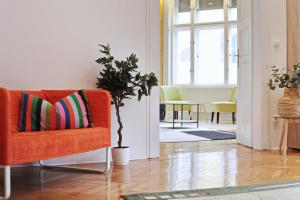 ブダペストにあるLuxury gold plated suite in calm central locationのリビングルーム(オレンジチェア、植物付)