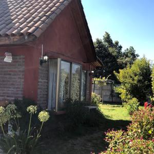 ein rotes Haus mit einem Fenster auf der Seite in der Unterkunft Casa de Campo Reina Margarita in Santa Cruz