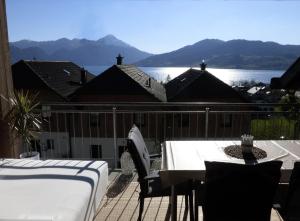 a balcony with a table and chairs and a view of the water at FeWo Atterseeperle - 80m2 mit See- und Gebirgsblick in Steinbach am Attersee