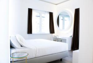 Dormitorio blanco con cama y espejo redondo en CiuriTaormina Maison de Charme, en Taormina