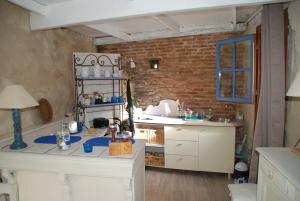 uma cozinha com armários brancos e uma parede de tijolos em les 2 studios indépendants du clos de l'Ange em Rieux