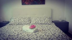 a bed with a pillow with a pink flower on it at Casa del Loto in Fiumicino