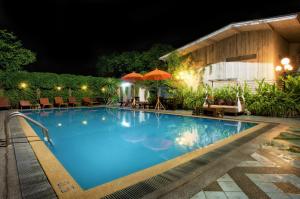 a swimming pool at night with chairs and umbrellas at Chiangmai Gate Hotel in Chiang Mai