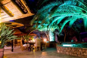 people sitting at a table in a restaurant with a palm tree at Etusis Lodge in Karibib