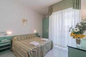 a hotel room with a bed and a vase of flowers at Residence Baltic in Cattolica