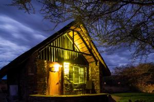 Cabaña pequeña de piedra con ventana iluminada por la noche en Etusis Lodge, en Usakos