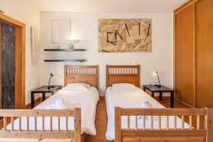 2 Betten in einem Zimmer mit 2 Tischen und 2 Bänken in der Unterkunft Villa do Cisne in Charneca + 47 Fotos