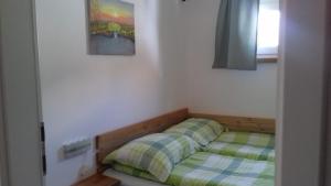 Una cama pequeña en una habitación con ventana. en Apartma Javoršček, en Bovec