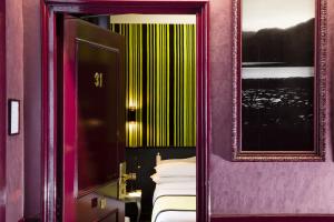 パリにあるホテル デザイン ソルボンヌの紫の壁のベッドルーム(鏡、ベッド付)