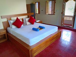 a bedroom with a large bed with red pillows at Uma Kutuh Bungalow in Ubud