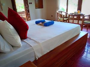 een groot wit bed met rode en blauwe kussens erop bij Uma Kutuh Bungalow in Ubud
