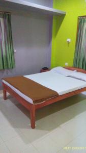 a bed with a wooden frame in a room at Roxel Inn in Port Blair