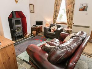 a living room with a leather couch and a fireplace at Crinan Canal Cottage No8 in Lochgilphead