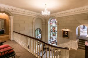 uma escadaria com um lustre e vitrais em Eshott Hall em Morpeth
