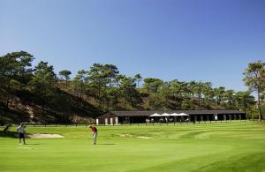 zwei Personen, die auf einem Golfplatz Golf spielen in der Unterkunft Villa do Cisne in Charneca