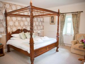 a bedroom with a four poster bed with white sheets at Llechwen Hall in Pontypridd
