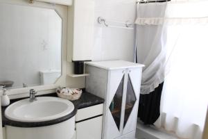 Un baño blanco con lavabo y espejo. en Roulas Cozy Apartments, en Artemida 16 fotos más